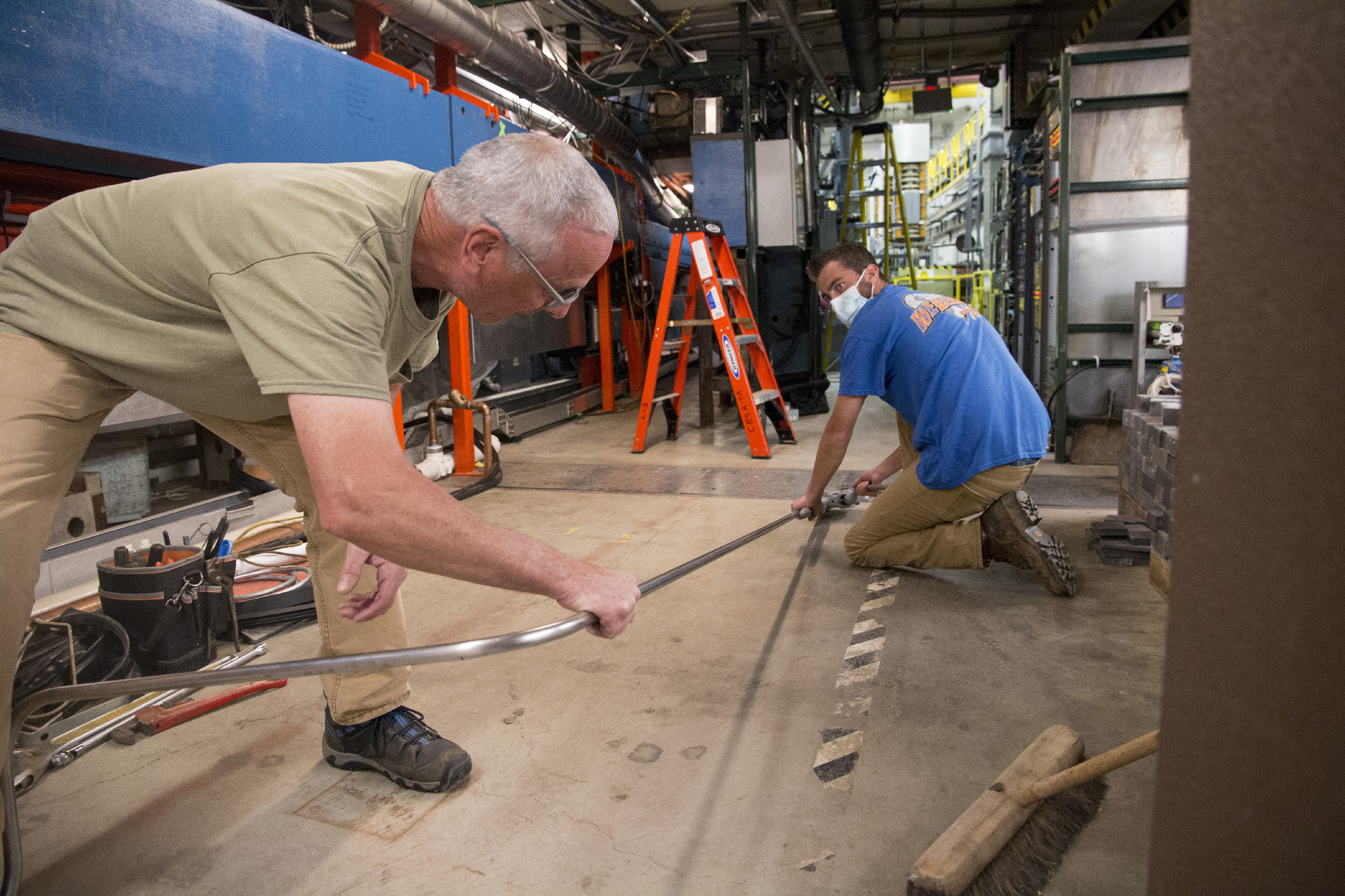 image of people holding a metal tube on the floor of the synchrotron