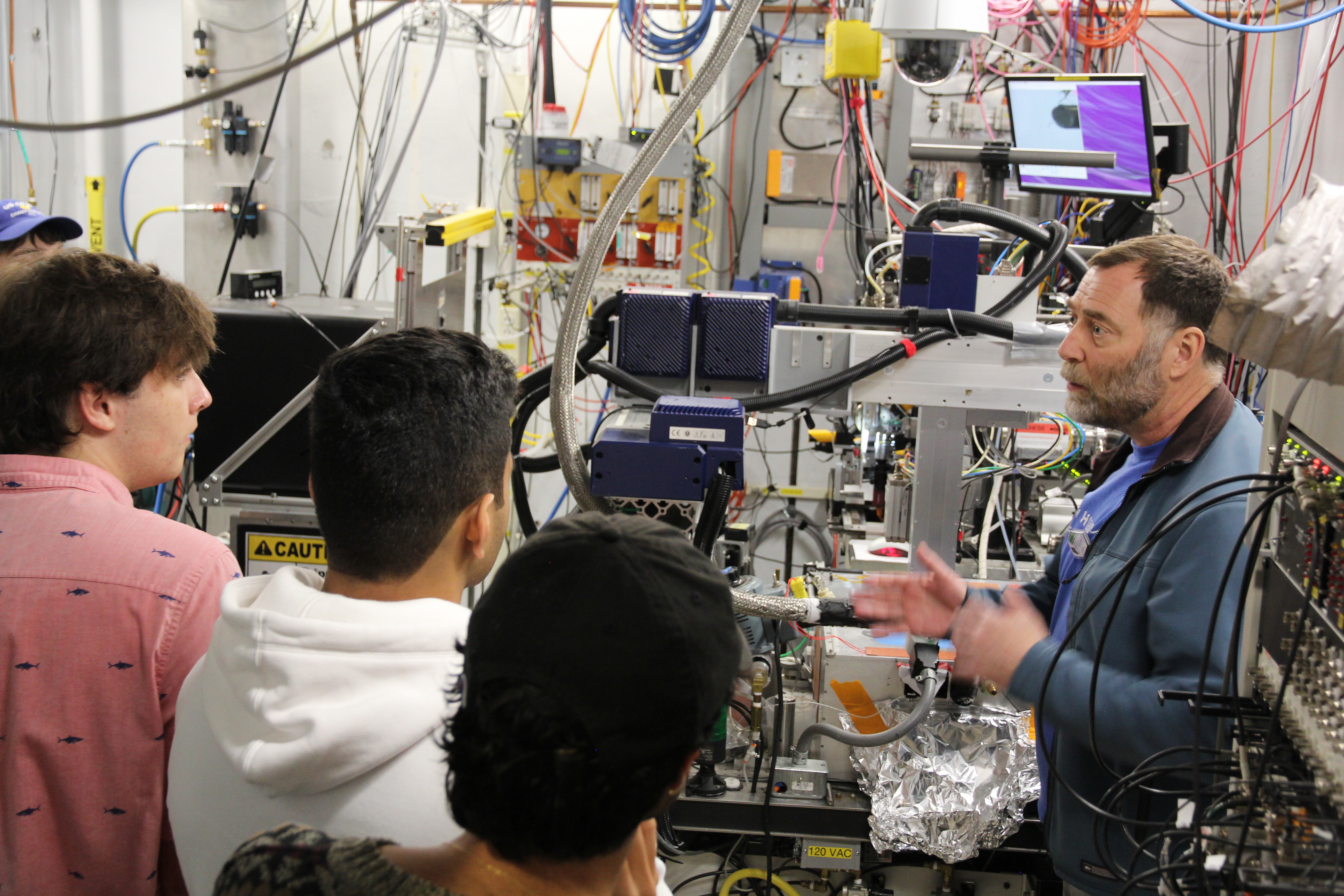 David Schuller shows beamline hardware to students at a macchess beamline