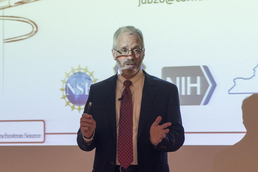 Joel Brock presenting with the NIH and NSF logos projected behind him.