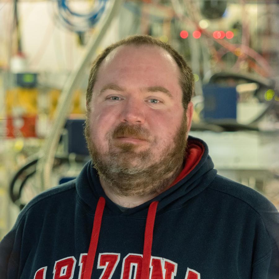 portrait of Aaron Finke with beamline components