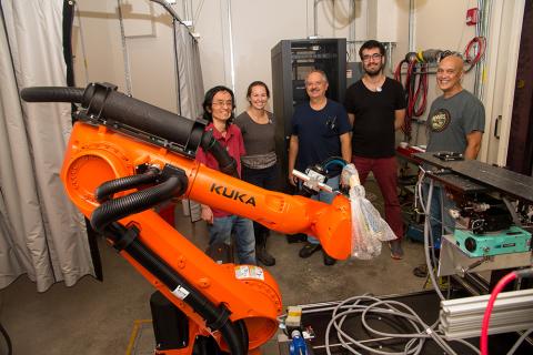 image of a group standing behind a large orange robot