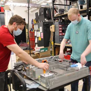 image of two people working on electric components