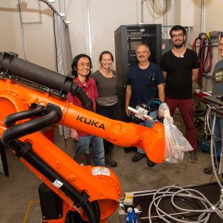 image of a group standing behind a large orange robot