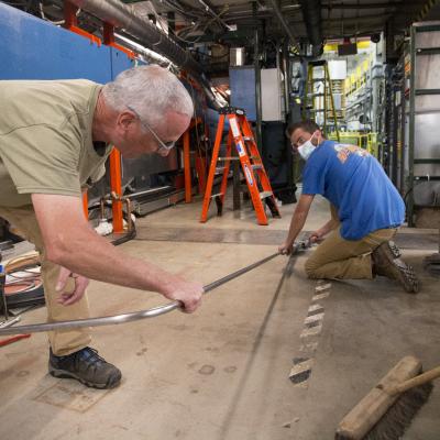 image of people holding a metal tube on the floor of the synchrotron